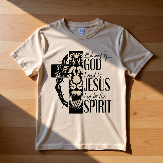 Beige t-shirt with a graphic design featuring a lion, cross, and text on a wooden surface.