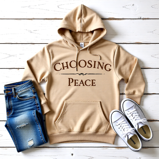 Beige hoodie with 'CHOOSING PEACE' text, blue jeans, and white sneakers on a wooden surface